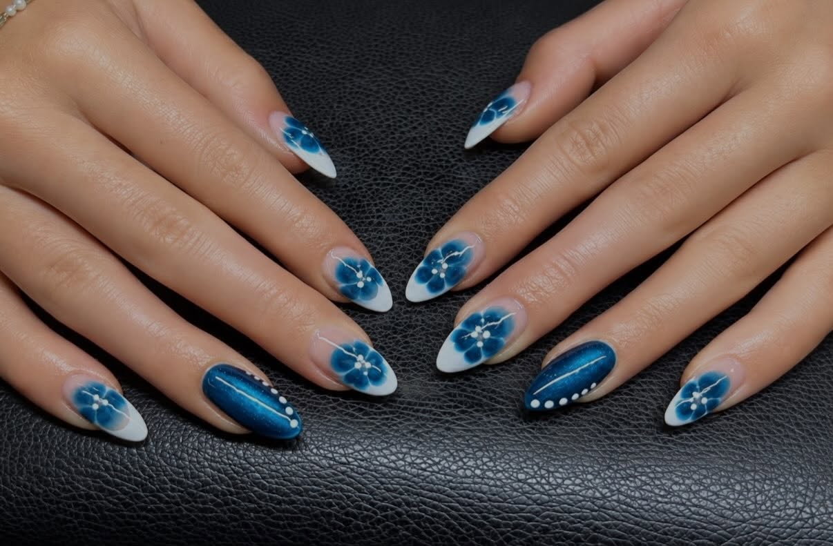 Amandelnagels met blauwe bloemen op een witte basis en een donkerblauwe accentnagel